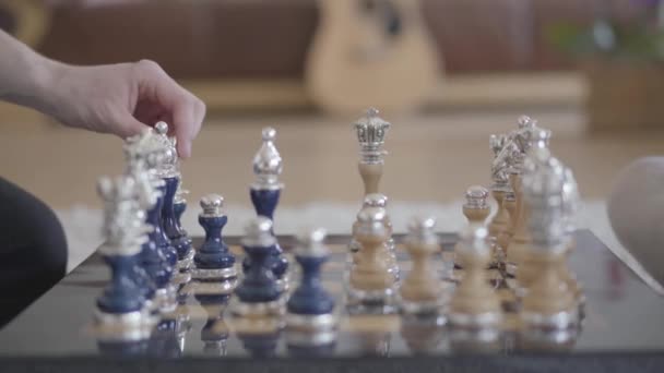 Dos personas irreconocibles jugando un hermoso ajedrez de lujo en la sala de estar en un ambiente acogedor, y alguien derribó un peón. De cerca. — Vídeos de Stock