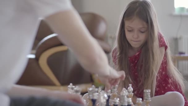 Padre irreconocible y niña jugando al ajedrez sentados en el suelo de cerca. La hija gana, ella está emocionada y feliz, la gente de cinco. De ocio familiar. Paternidad, infancia — Vídeos de Stock