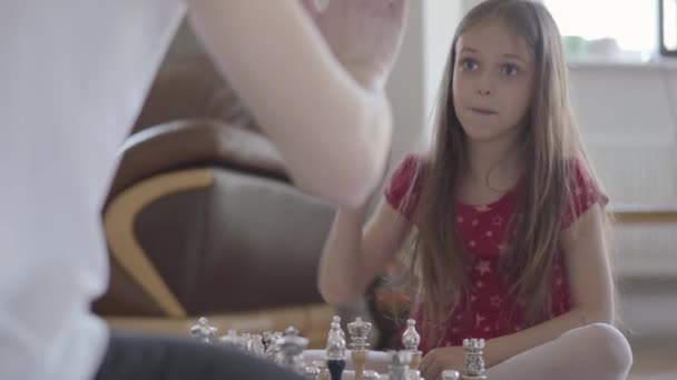 Portrét neidentifikovatelného otce a holčičky hrající šachy na podlaze zblízka. Dcera vyhrává, je vzrušená a šťastná, lidi na páté. Rodinný čas. Otcovství, dětství — Stock video