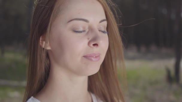숲에서 갈색 머리를 가진 우아한 귀여운 젊은 여성의 클로즈업 초상화 — 비디오