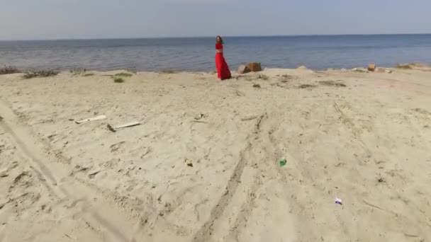 Young graseful woman in red long dress dancing raises hands on the big stone near spectacular view of blue sea water and amazing sky. Contemporary dancer practicing outdoors. Shooting on drone. Slow — Stock Video
