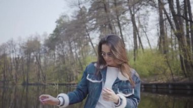 Güneş gözlüğü ve bir göl veya nehir üzerinde bir tekne üzerinde yüzen bir kot ceket sevimli bir genç kadın Portresi. Güzel esmer aktif bir gün kapalı rahatlatıcı ya da doğanın tadını çıkararak seyahat.