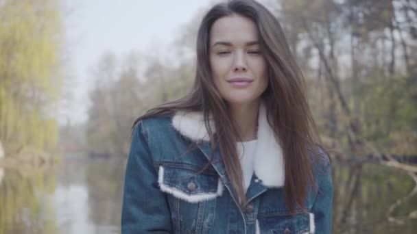 Portret van gracieuze lachende vrouw die in de camera kijkt. Mooi landschap, rivier op achtergrond — Stockvideo