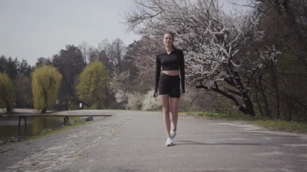 Slim sports young woman in sportswear running on the riverbank. Active lifestyle, sport. The lady keeping her body in shape. Beautiful landscape. Bottom view — Stock Video