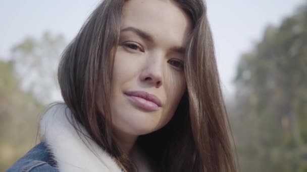 Retrato de cerca de una joven y bonita mujer sonriente mirando a la cámara. Hermoso paisaje, río en el fondo — Vídeo de stock