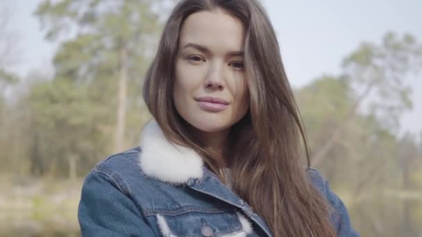 Retrato de una joven y bonita mujer sonriente mirando a la cámara. Hermoso paisaje, río en el fondo — Vídeo de stock