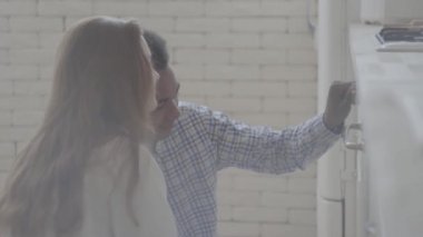 Yakışıklı afro-amerikan erkek evde birlikte yemek ile Pretty genç beyaz kadın. Mutlu çift fırında gülümseyerek bakıyor. Gençlerin eğlence