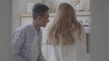 Uzun sarı saçlı ve mulatto genç adam katta oturan ve fırına bakarak kadın arkasında. Arkadan ateş ediyor. Aile ilişkileri.