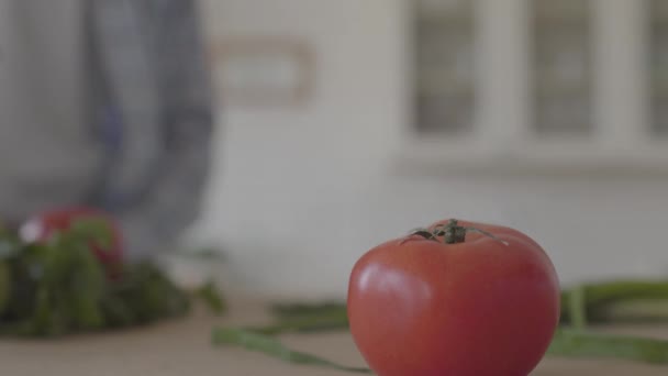 Feche o tomate fresco deitado na mesa. A mão do homem afro-americano levando o vegetal e ele vai embora. Estilo de vida saudável — Vídeo de Stock