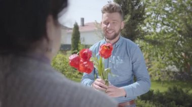 Yakışıklı torunu büyükannesini ziyaret ediyor, ona lale buketi getiriyor. Büyükannesini kucaklayan sakallı adam. İnsanlar gülümsüyor. Eve adam davet eden bir kadın. Aile ilişkisi, doğum günü