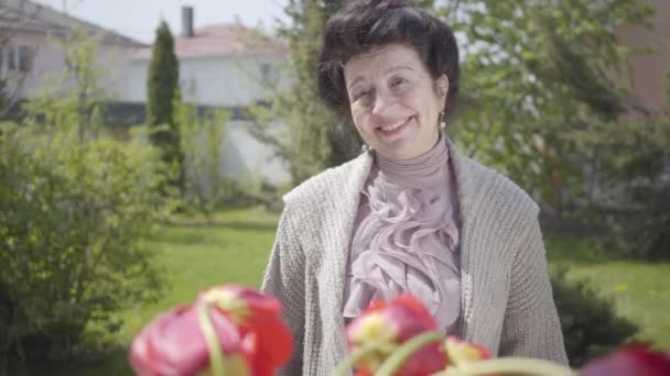 Carino nipote visitare la nonna, portando il suo bouquet di tulipani. L'uomo barbuto che abbraccia sua nonna. La gente sorride. Una donna che invita un ragazzo in casa. Relazione familiare, compleanno festivo — Video Stock