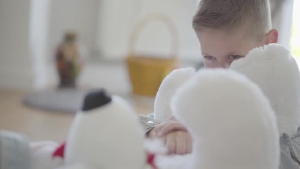 Close-up portret tweeling jongen en meisje zittend op de vloer in de woonkamer en weet niet hoe te delen tussen hen een grote Taddy Beer. Kinderen trekken speelgoed aan elkaar om het te bezitten — Stockvideo