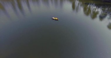 Güzel bir geniş yansıtıcı göl veya nehir boyunca küçük tekne tekne iki kişi. Aktif yaşam tarzı, doğayla bağlantı. Drone çekim, üstten görünüm, havadan çekim
