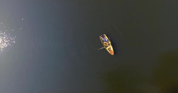 Two girls in the small boat on a beautiful reflective river. Active lifestyle, connection with nature. Drone shooting, top view, aerial shot. — Stock Video