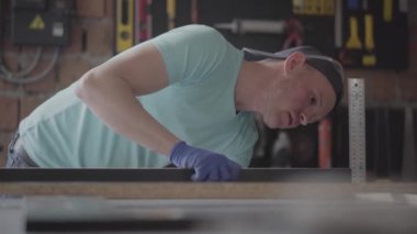 Yetenekli marangoz onun ahşap atölyesinde yonga levha detay parça ölçümleri yapma, arka planda birçok araç. El üretim kavramı. Craftman bir atölyede çalışıyor.