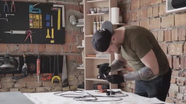 Carpenter in cap working with electrical wires. To much tools for furniture manufacture. — Stock Video