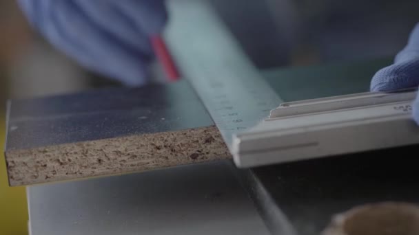 De handen van de timmerman in de handschoenen markeren van de lijn op de MDF-plaat waar moet worden gesneden, dan weg te nemen van het bord. Close-up weergeven. Werkproces. Concept van hand productie — Stockvideo