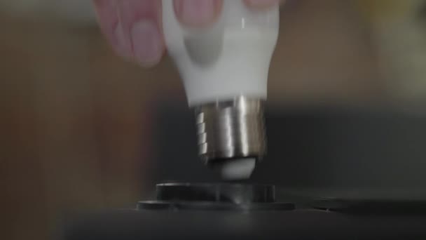 Mano avvitare una lampada all'interno di una lampadina e la sua luce. Produzione manuale. Artigiano lavora in un laboratorio . — Video Stock