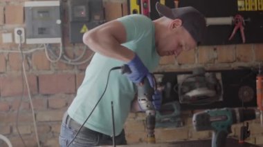 Zanaatkar mühendis portresi küçük bir atölye nin arka plan üzerinde alet ile bir delik delme üzerinde duruldu. El üretim kavramı. Craftman bir atölyede çalışıyor.