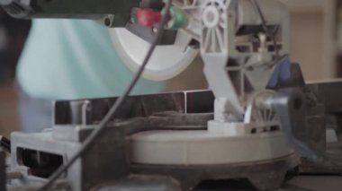 Arka planda yaptığı çalışmaları yaparken koruyucu eldivenler ile erkek ellerini kapatın. Mobilya fabrikasında çalışma süreci. Marangozluk mesleği. Ön planda küçük dairesel testere