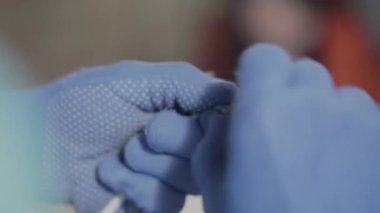 Mavi eldivenli elektrikçinin yakın elleri kabloları ölçüyor ve kesiyor. Bir adam atölyede çalışıyor. El üretimi kavramı.