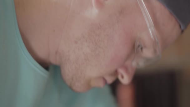 Närbild porträtt av unga Master Engineer i färg glasögon fokuserat på borrning ett hål med perforator — Stockvideo