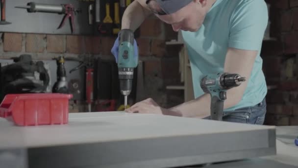 Ingeniero maestro de habilidades de retrato enfocado en perforar un agujero con herramienta en el fondo de un pequeño taller con instrumentos — Vídeo de stock