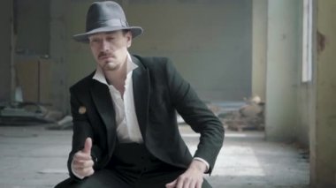 Bir şapka portre yakışıklı kendine güvenen adam kusuyor ve terk edilmiş bir binada oturan sikke yakalar. Mafyanın başı boş bir binada bekliyor. Yavaş çekim. Terk edilmiş harap