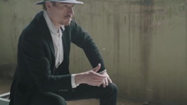 Bir şapka portre yakışıklı kendine güvenen adam kusuyor ve terk edilmiş bir binada oturan sikke yakalar. Mafyanın patronu boş bir binada bekliyor. Yavaş çekim. Terk edilmiş harap bina