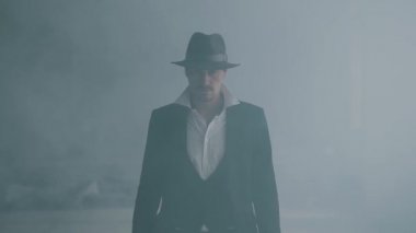 Fedora şapka ve klasik takım elbise portre acımasız gangster dumandan yürümek. Yavaş çekim. Terk edilmiş harap bina. Kendine güvenen işadamı rahatlatıcı
