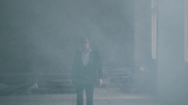 Fedora şapka ve klasik takım elbise portre emin acımasız gangster dumandan yürümek. Yavaş çekim. Terk edilmiş harap bina. Kendine güvenen işadamı rahatlatıcı