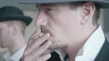 Eski harap binada yürüyen iki sigara içen gangsterin portresini kapatın.