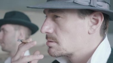 Eski harap binada yürüyen iki sigara içen gangsterin yakın çekim portresi.