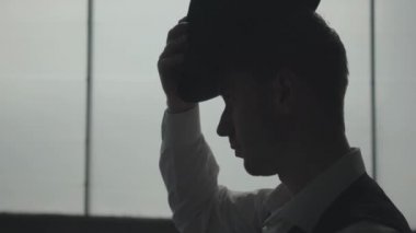 Yakın çekim genç adam kafasına şapka takıyor. Terk edilmiş harap bina. Kendine güvenen işadamı rahatlatıcı