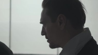 Yakışıklı kendine güvenen adamın büyük pencerenin önünde kafasına şapka takmaportresi. Mafyanın başı toplantıya hazırlanıyor. Ceza dairesi portresi. Kendine güvenen işadamı rahatlatıcı