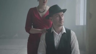 Yakışıklı kendine güvenen mafya babası, terk edilmiş bir binada oturan bir şapka ve yelek. Kırmızı elbiseli zarif kadın arkadan geliyor ve gülümseyen adama sarılıyor. Gangsterler Mutlu çift