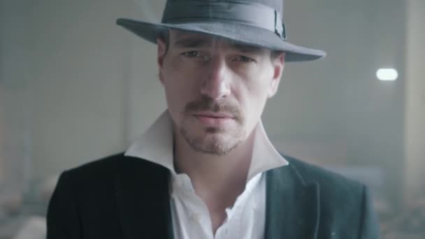 Un bel homme confiant dans un chapeau fumant du cigare dans un immeuble abandonné. Le chef de la mafia est dans un bâtiment vide. Portrait de l'autorité criminelle, gros plan . — Video