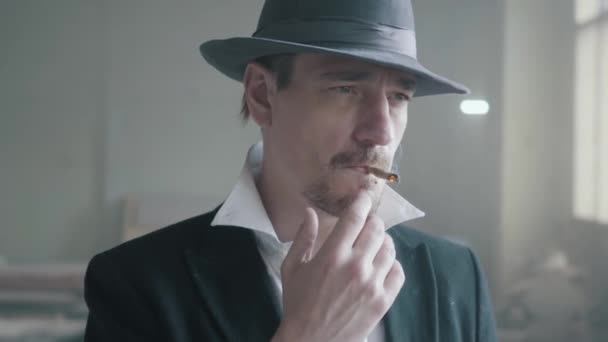 Portrait handsome confident man in a hat smoking cigar in an abandoned building. The head of the mafia is in an empty building. Criminal authority portrait, close up. — Stock Video