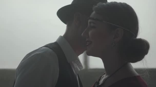 Knappe Zelfverzekerde man in een hoed Whispering grap op het oor van de elegante dame, ze is lachen. Het hoofd van de maffia met zijn jonge lieve vrouw. Strafrechtelijk gezag, coole jongens, maffia — Stockvideo