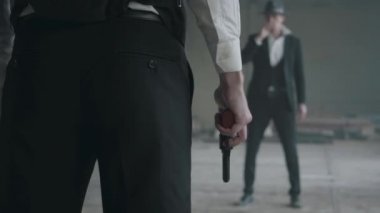 Resmi takım elbiseli tanınmayan vahşi adam elinde silah ve sigara ile diğer adam karşısında durmak. Suç gruplandırması. Terk edilmiş harap bina. Kendine güvenen yasadışı işadamı.