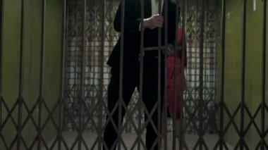 Takım elbise ve şapka portre uzun boylu adam kapıyı açar ve karanlık oda içinde zarif kırmızı bir elbise içinde kendine güvenen güzel bir kız geçer. Retro, vintage tarzı. Mafya hayatı