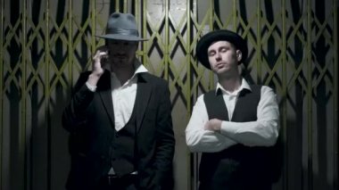 Şapkalı, birbirine yakın duran, bekleyen, kendine güvenen iyi giyimli iki adamın portresi. Aynı anda her iki kişi çerçeve bırakın. Ceza dairesi, mafya, suç çetesi