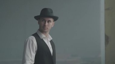 Terk edilmiş bir binada kameraya bakan şapkalı yakışıklı kendine güvenen bir adam portresi. Mafyanın patronu boş bir binada. Ceza dairesi portresi. Kendine güvenen işadamı rahatlatıcı.