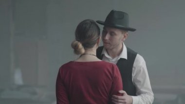 Yakışıklı kendine güvenen bir adam kameraya sırtını ile ayakta zarif bayan kulağına şaka fısıldayan, o gülüyor. Retro, vintage tarzı
