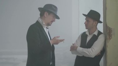 Portre iki emin yetişkin erkek fedora şapka kırık durty yerde ayakta ve konuşuyor. Terk edilmiş harap bina. Kendine güvenen bir işadamı rahatlatıcı. Mafya klanı. Suç gruplandırma.