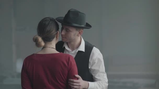 Retrato guapo hombre confiado en un sombrero susurrando broma en el oído de la señora elegante que de pie con su espalda a la cámara, ella se ríe. Retro, estilo vintage — Vídeo de stock