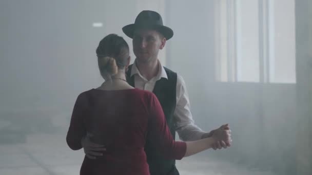 Retrato hombre en sombrero fedora, trajes clásicos y mujer en tela de estilo bailando en edificio abandonado . — Vídeos de Stock