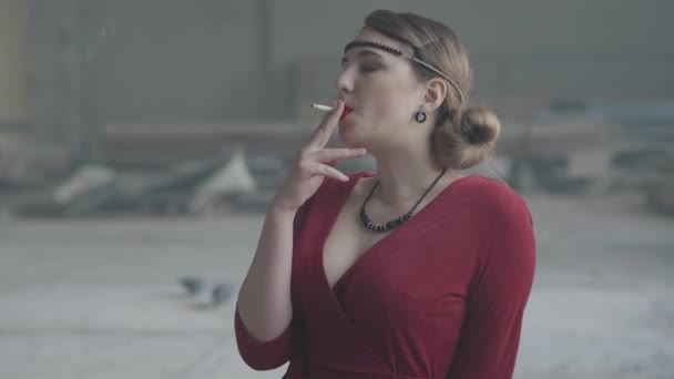 Portre kendine güvenen genç kadın eski tarz kumaş ateş sigaret. Terk edilmiş harap bina. — Stok video