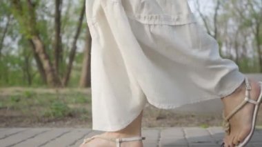 Parkta yürüyen inanılmaz beyaz elbiseli mutlu güzel kadın. Yavaş çekim