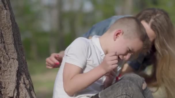 Portret małego chłopca płacze i matka jest kojący jej syna na zewnątrz. Relacja Mama i syn. Rekreacja na świeżym powietrzu. — Wideo stockowe